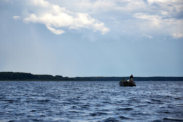 A boat sails down the river against a blue sky with clouds