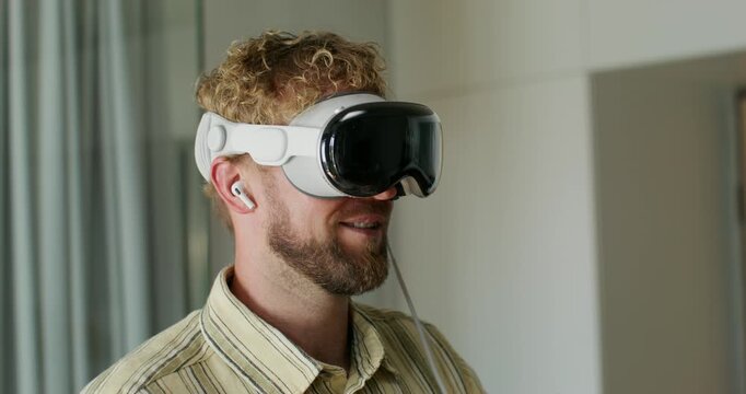 A man in a virtual reality headset talks and moves his hands typing on a virtual keyboard. Close-up of his face