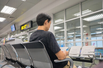 business concept with asian man sit on chair and work with tablet in airport