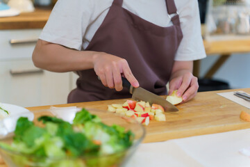 Closeup hands of asian women using knife to chopping slices apple on cutting board to preparing fruits of ingredients for cooking breakfast meal and salad while making healthy food lifestyle in home