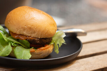 Close-up Hamburger with meat, pickles and ketchup in disk on wooden table.