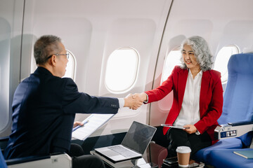 Business meeting in airplane, asian Mature businessman in private jet is talking with Mature female colleague and documents, business people flying in airplane