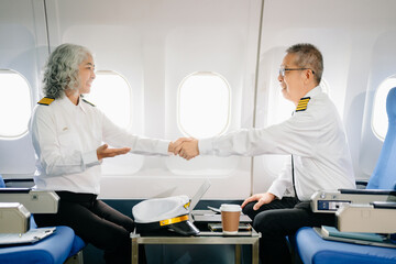 Fototapeta premium Mature commercial male pilot Beautiful middle aged woman airplane captain instructor has a meeting, discussion with aircrew team