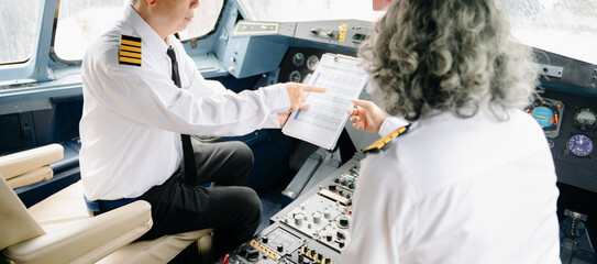 Mature commercial male pilot Beautiful middle aged woman airplane captain instructor has a meeting, discussion with aircrew team