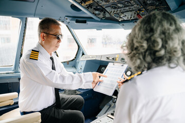 Mature commercial male pilot Beautiful middle aged woman airplane captain instructor has a meeting,...
