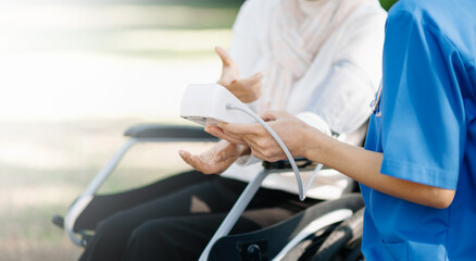 Elderly asian senior woman on wheelchair with Asian careful caregiver and encourage patient, walking in garden. with care from a caregiver