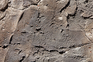 Wall with a rough texture and a few cracks. The wall is made of concrete and has a grey color