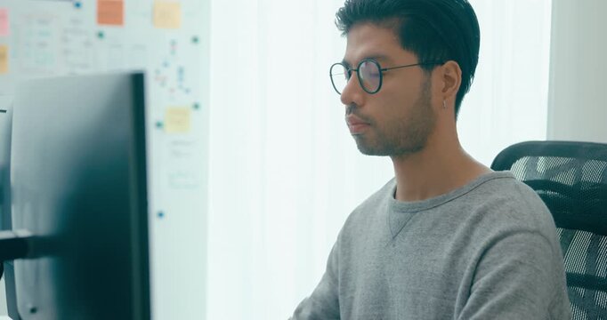 Young adult Asia male freelance eyeglasses typing write prompt AI bot IT app smart program nomad, video game, terminal with coding, user interface, designer, big data center on desktop computer.