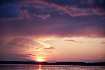 blurred background view of summer sunset with the reflection of the sun on the river