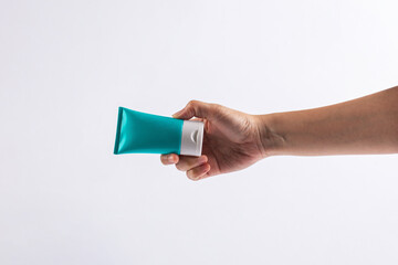 Blue cosmetic bottle, Skin care or sunscreen cosmetic in hand on white background.