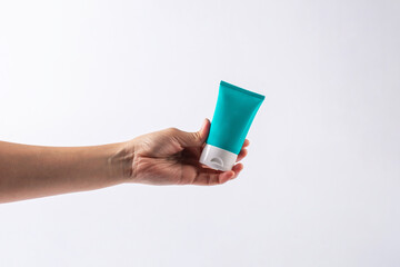 Blue cosmetic bottle, Skin care or sunscreen cosmetic in hand on white background.