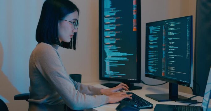 Young Asia female freelance eyeglasses typing write prompt AI bot IT app smart program nomad, video game, terminal with coding language, designer, big data center on desktop computer in night office.