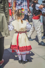 Little girl in national Bulgarian clothes at folk festival, back view
