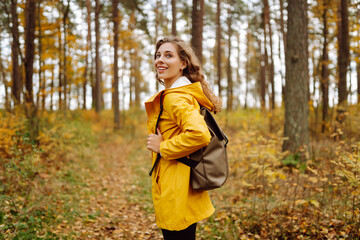 Smiling young woman enjoys the autumn weather in the forest. Autumn landscape.