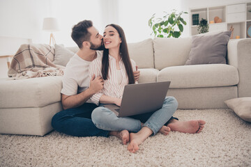 Photo of adorable sweet couple wear casual shirts kissing enjoying weekend together texting device indoors room home house