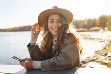 Young woman relaxing drinking coffee against the backdrop of a lake. Travel, camping, nature concept.