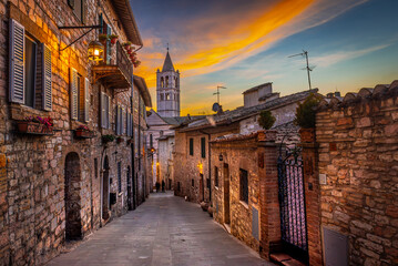 Assisi, Italy. View of the Basilica of Santa Chiara from Via Sermei at sunset. Narrow street with...