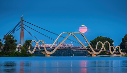 Pink Thunderstorm Full Moon rises on the background of pedestrian bridge in Obolon district, Kyiv, Ukraine