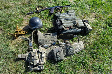 Kalashnikov assault rifle, soldiers helmets and bulletproofs put on a ground