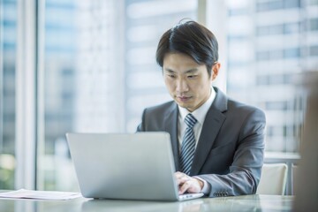 ノートパソコンで保険データを分析する日本人実業家
