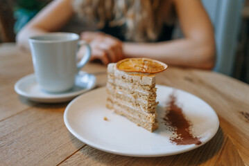 Delicious slice of cake with a cup of coffee on a wooden table in a cozy cafe setting. 