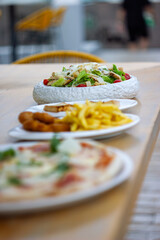 Three different dishes, with a salad in focus and the other dishes slightly blurred.
Tres platos...