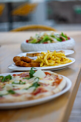 Three different dishes, with chicken nuggets and fries in focus and the other dishes slightly...