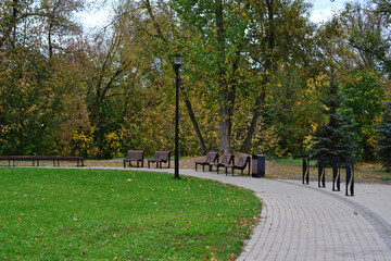 a park with benches and a green lawn and a pathway