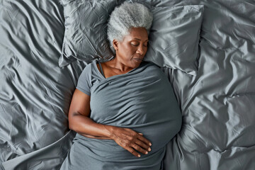 An elderly woman is resting on a bed