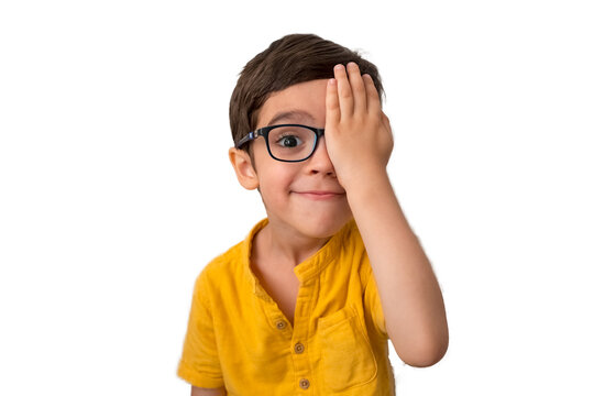Portrait of little boy in glasses reviewing eyesight. Kid with eyeglasses close one eye with hand to chech vision in front of white background. Vision testing concept. Lazy eye, amblyopia, strabismus.