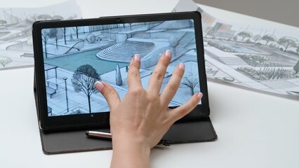 Woman architect designer works on graphic tablet display with stylus, hand drawing coloring project of city park. Creativity and modern technology.