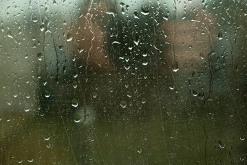 Water drops on glass window with autmn forest background