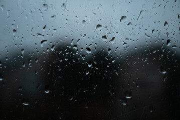 Water drops on glass window with autmn forest background