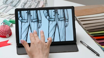 Woman fashion designer works on digital graphic tablet touch screen with illustration of clothing collection sketch. Creativity and modern technology.