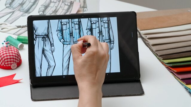 Woman fashion designer works on graphic tablet display with stylus, hand drawing coloring project men's clothing. Creativity and modern technology.