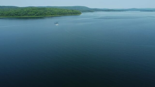 Excursion de ski nautique film&eacute; du ciel par un drone sur les eaux calmes et bleues du Lac Matap&eacute;dia. Bateau fait demi-tour et provoque de jolies vagues pour r&eacute;cup&eacute;rer le skieur nautique fatigu&eacute;.