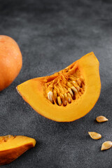 Fresh whole and sliced orange pumpkin with seeds on a gray background. Cooking concept.