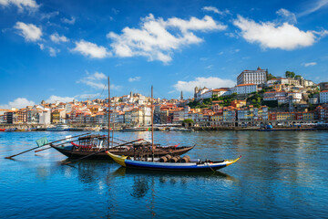 Fototapeta premium View of Porto city and Douro river with traditional boats with port wine barrels from famous tourist viewpoint Marginal de Gaia riverfront. Porto, Vila Nova de Gaia, Portugal