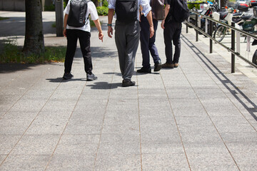 夏の昼の都市の街で歩くサラリーマンたちの姿