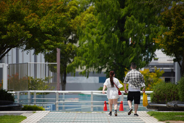 真夏の昼の都市の繁華街で歩く二人の若い男女の姿