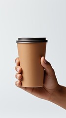 A hand holding a stylish disposable coffee cup against a minimalistic background, perfect for coffee-related themes.