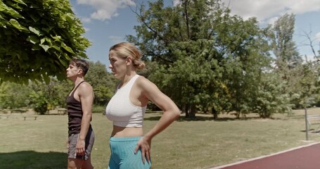 A young couple takes a break from jogging in a sunny park, with the fit man and woman resting and catching their breath after their run, enjoying a moment of relaxation. - Powered by Adobe