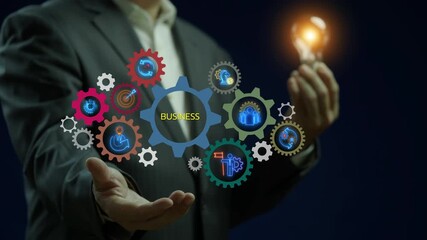 Businessman showing glowing neon line gears banner of business concept with icons of ideas, management, strategy, leadership, process, team, implementation and goals on virtual screen.