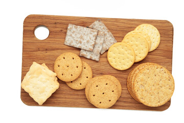 Different crackers on cutting board isolated on white background. Vertical photo