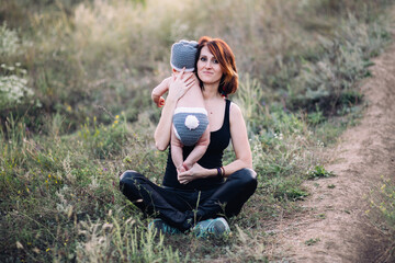 Young mother holding her baby boy in hands, outdoors in summer in sun rays