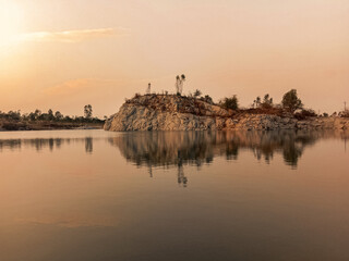 Tranquil Sunset Over a Serene Lake with a Rocky Outcrop Reflecting on Calm Waters