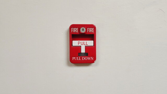 Vertical image of Red emergency fire alarm with white push-down switch. Installed on white cement walls inside the building. As background for warning and security system. Emergency fire warning
