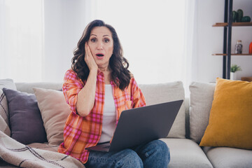 Photo of adorable shocked lady wear plaid shirt getting emails modern device indoors room home house