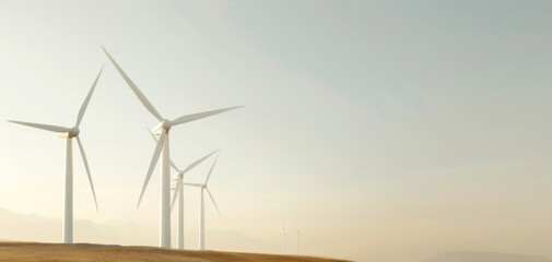 Fototapeta premium Wind turbines on a rural landscape under clear sky, representing renewable energy and sustainable power generation.