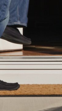 Vertical view of a man picking up a package from outside his front door.	
